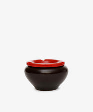 The Mix & Match Ashtray, a round black ceramic piece with a bold red rim, is displayed against a plain white background.