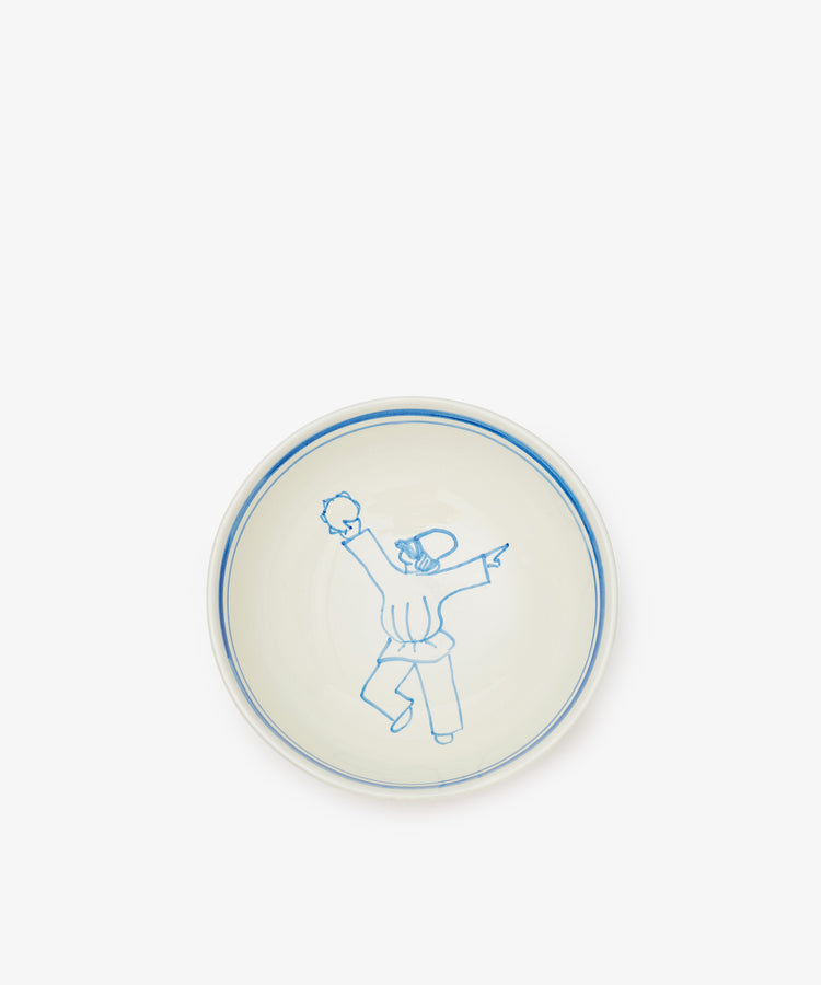 The Folk Cereal Bowl, Jester is a white ceramic bowl with a blue rim, featuring a simple blue line drawing of a jester-like figure—evoking hand-painted Italian ceramic style.