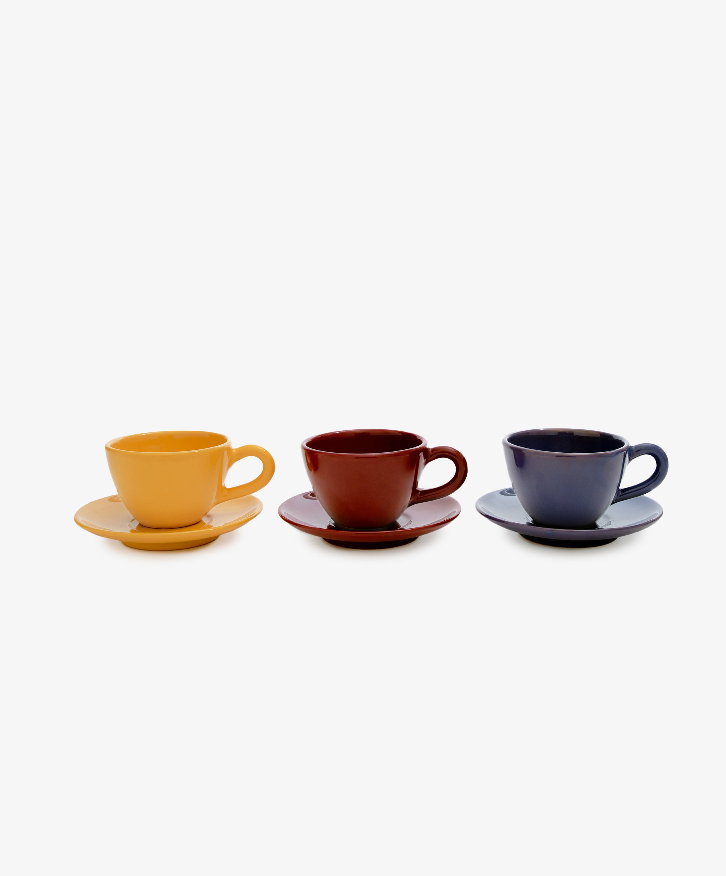 Row of three Guido Coffee matching cup and saucers in mustard, burgundy, and dark purple-blue glazed ceramic.