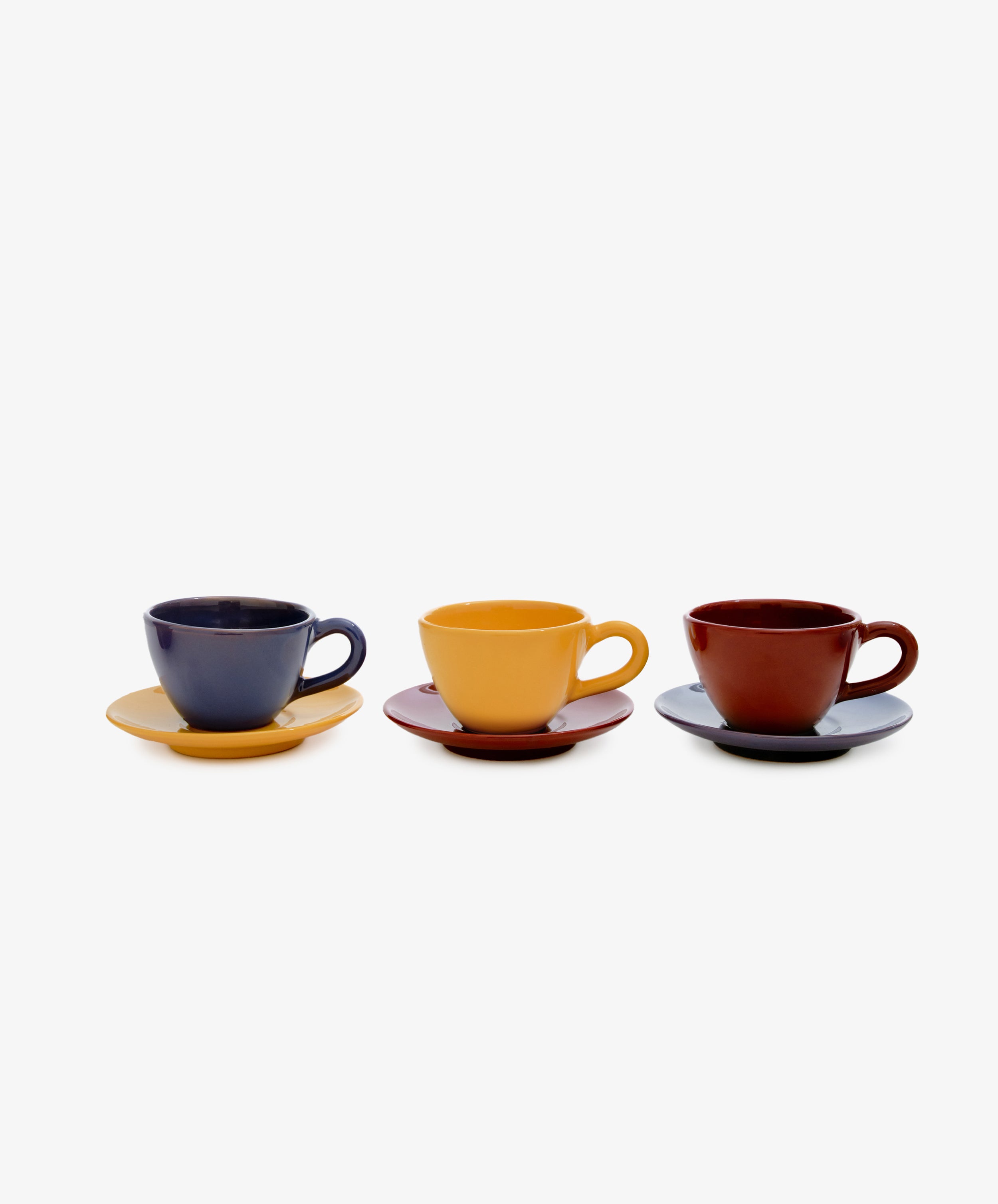 Row of three Guido Coffee cup and saucers mismatched in mustard, burgundy, and purple-blue glazed ceramic.