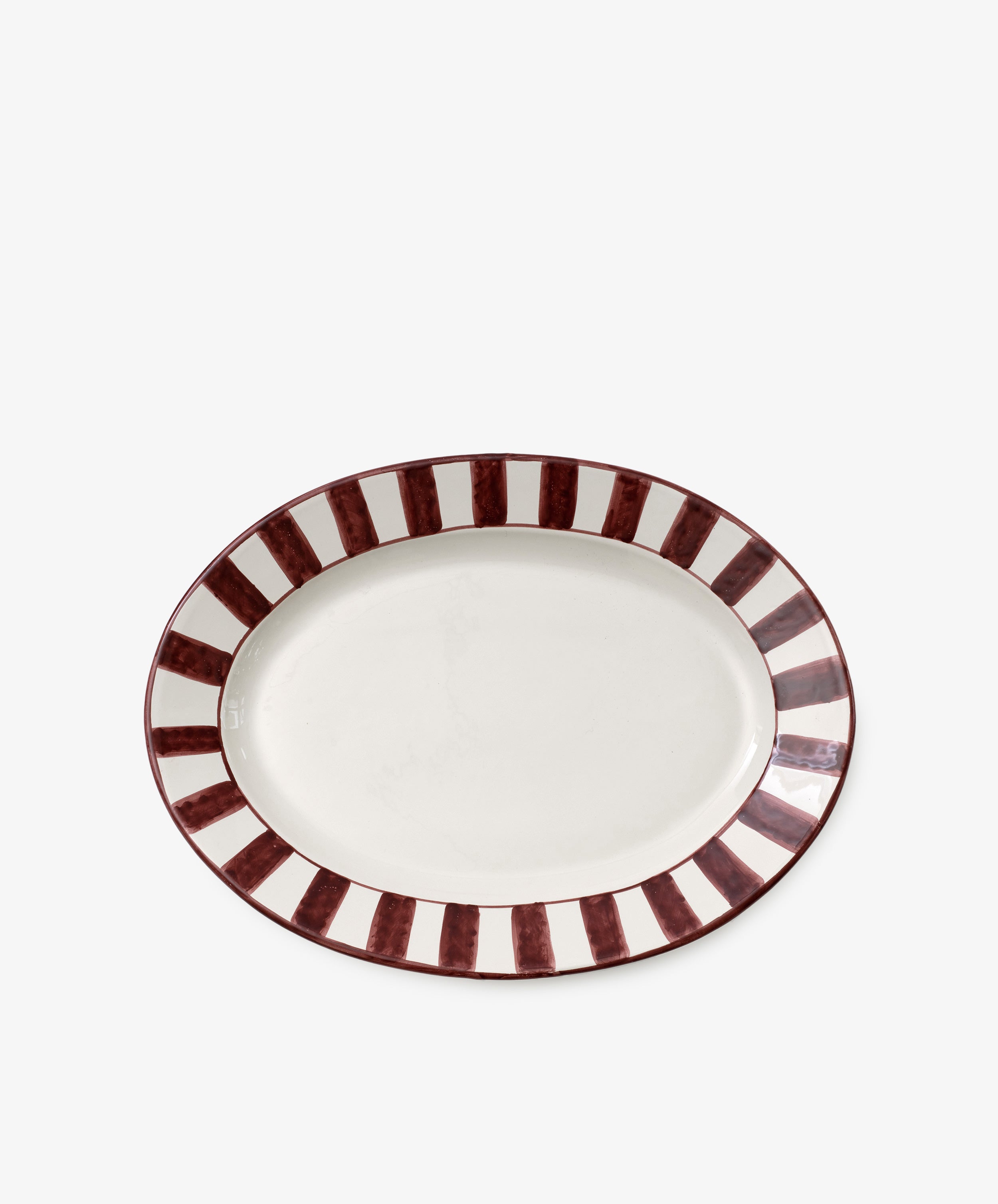 The Julius Oval Serving Platter is a white ceramic dish with bold, hand-painted maroon vertical stripes around the border for a striking look.