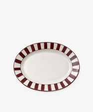 The Julius Oval Serving Platter is a white ceramic dish with bold, hand-painted maroon vertical stripes around the border for a striking look.