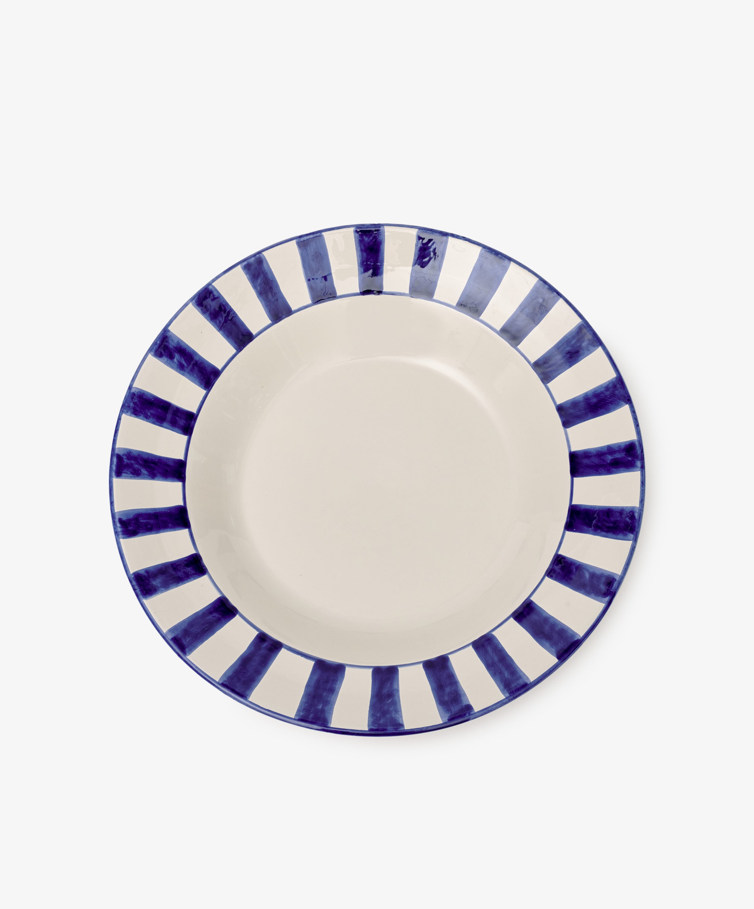 The Julius Serving Platter is a round ceramic piece with a cream center and a border of alternating dark blue and white stripes, ideal for serving appetizers or desserts.