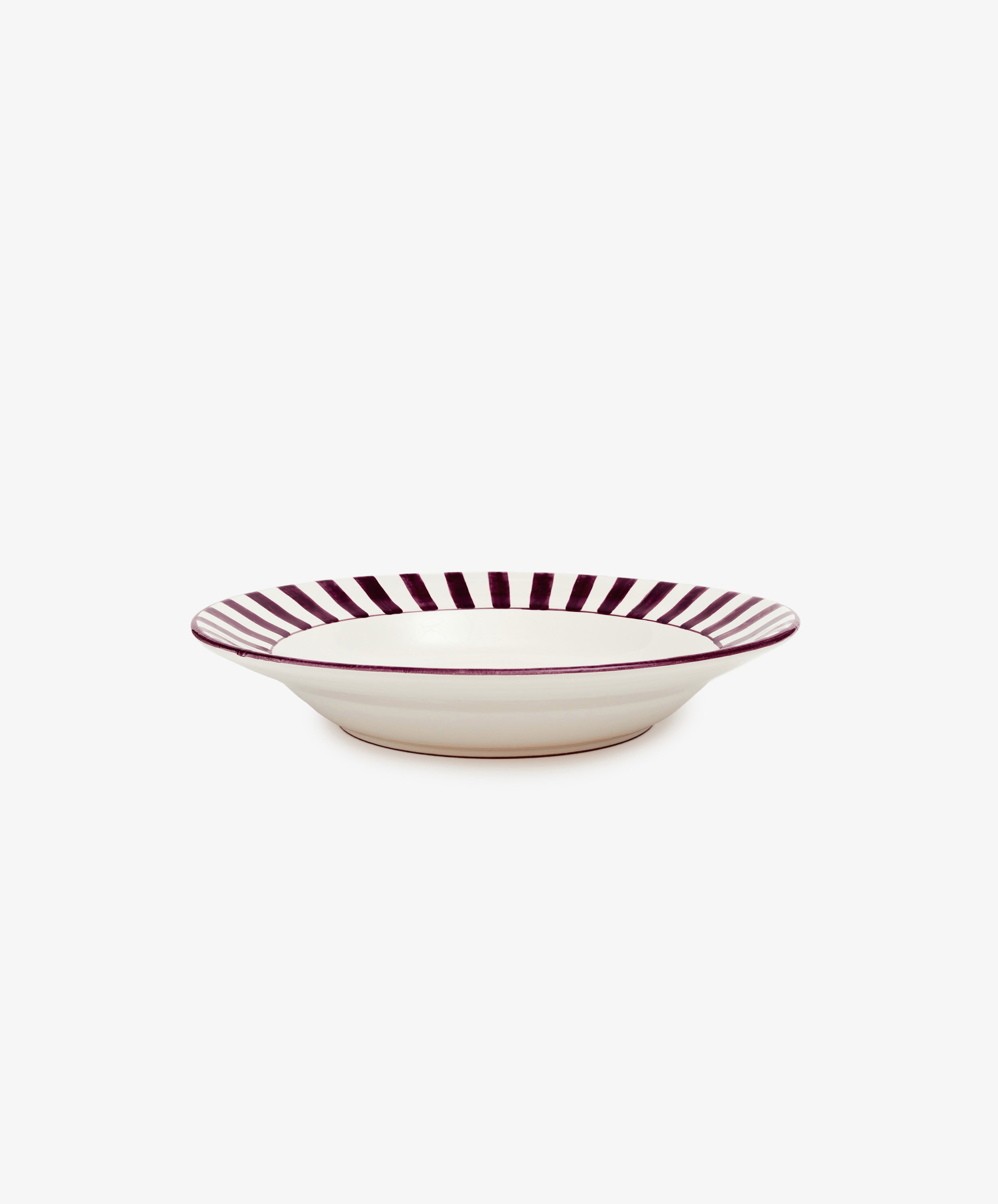 Julius Serving Bowl by Enza Fasano. White ceramic bowl with burgundy striped border motif, angled side view.