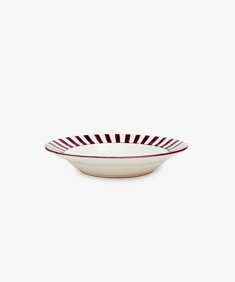 Julius Serving Bowl by Enza Fasano. White ceramic bowl with burgundy striped border motif, angled side view.