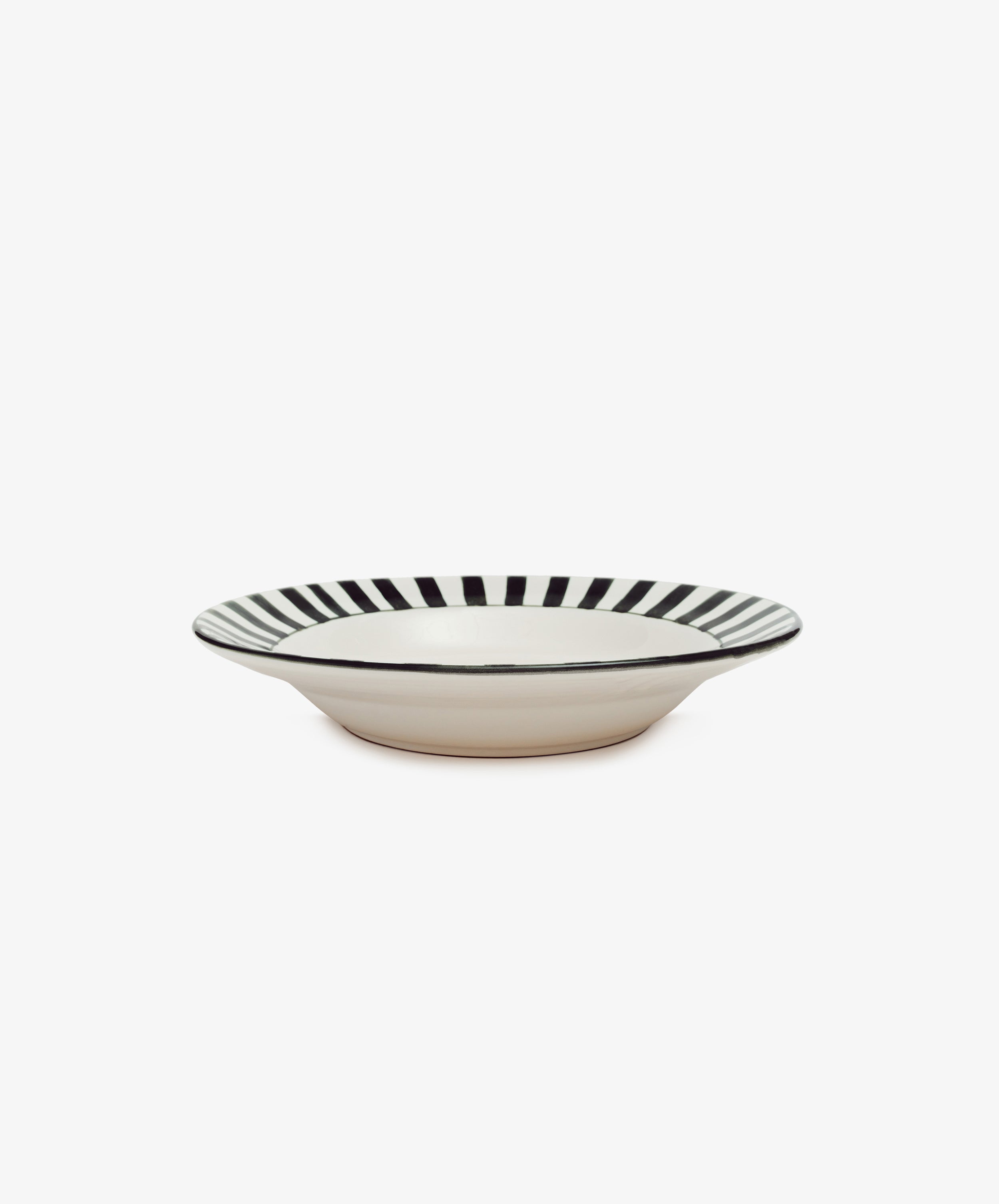 Julius Serving Bowl by Enza Fasano. White ceramic bowl with green stripes border motif, angled side view.