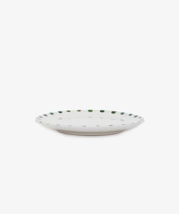 Nina Small Plate. White glazed ceramic plate with green painted rim details, angled side view.