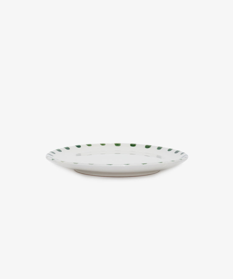 Nina Small Plate. White glazed ceramic plate with green painted rim details, angled side view.