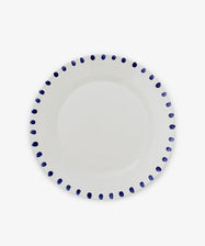 The Nina Serving Plate is a white ceramic plate featuring evenly spaced blue dots around the rim, shown against a plain white background.