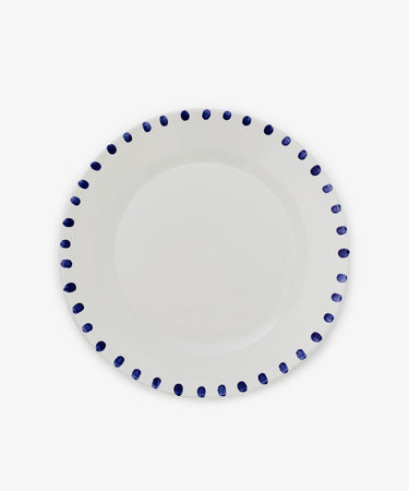The Nina Serving Plate is a white ceramic plate featuring evenly spaced blue dots around the rim, shown against a plain white background.