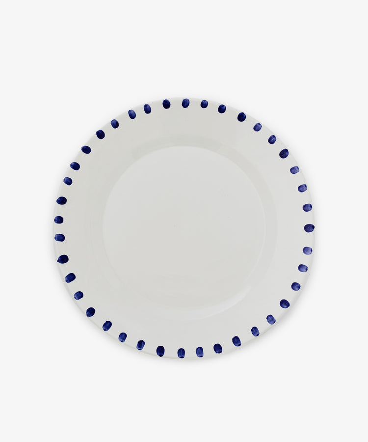 The Nina Serving Plate is a white ceramic plate featuring evenly spaced blue dots around the rim, shown against a plain white background.