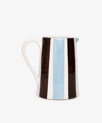 The Mina Jug is a hand-painted Italian pitcher with a handle, featuring vertical brown, white, and light blue stripes on a white background—perfect for adding charm to any setting.