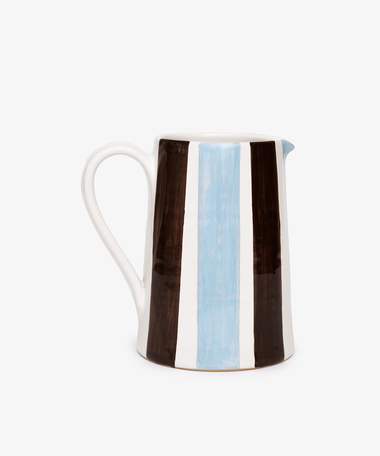 The Mina Jug is a hand-painted Italian pitcher with a handle, featuring vertical brown, white, and light blue stripes on a white background—perfect for adding charm to any setting.