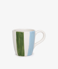 The Mina Mug is a white ceramic mug, hand-painted with vertical green and blue stripes inspired by Mediterranean designs, displayed on a plain white background.