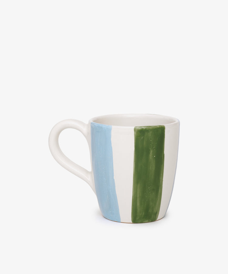 The Mina Mug is a white ceramic Mediterranean-style mug with a large handle, decorated with vertical blue and green stripes on the side, shown on a plain white background.