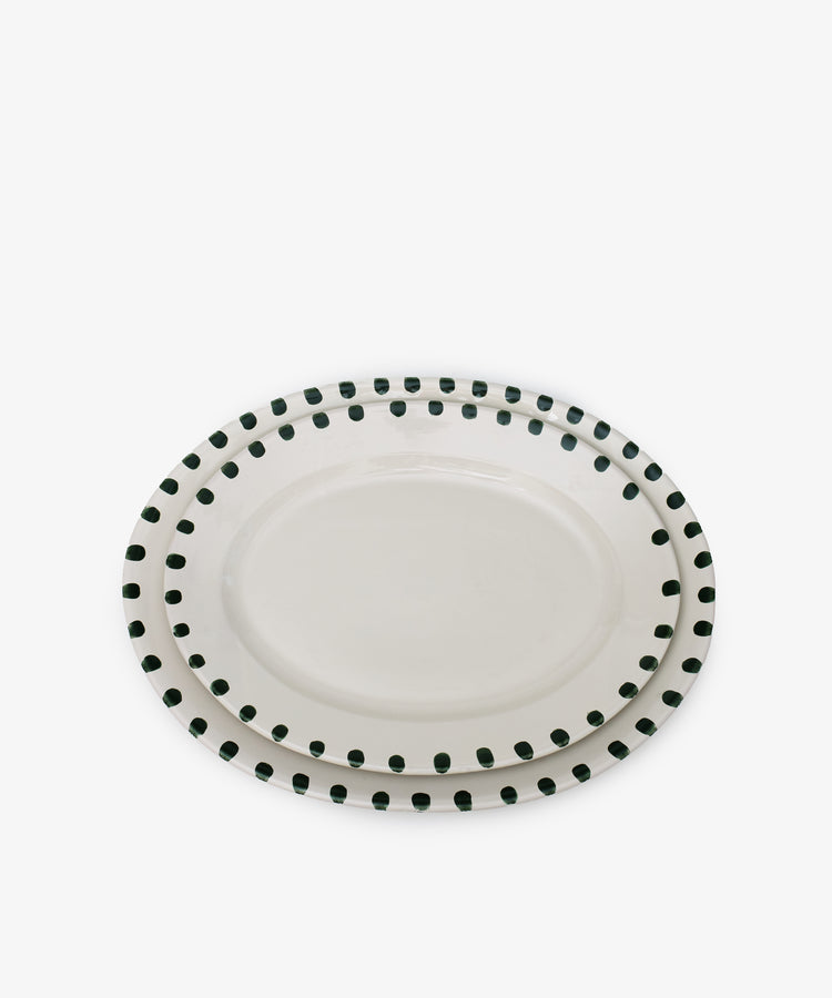 The Nina Oval Serving Platter set includes two hand-glazed ceramic platters with white centers and black dotted rims, stacked together—an entertaining essential for any gathering.