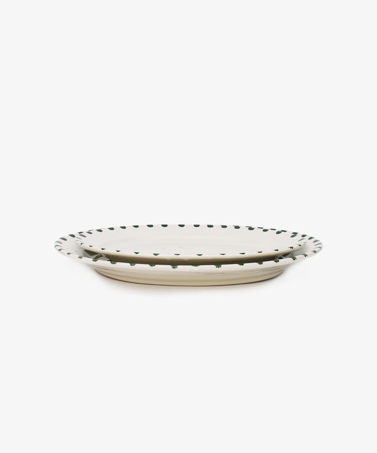 The Nina Oval Serving Platter is a hand-glazed ceramic plate with a beige base and small black dots along the rim—an entertaining essential perfect for serving at any gathering.