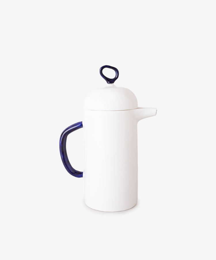 The Cafetière is a white ceramic coffee maker featuring a dark blue handle and matching loop on the lid, shown on a plain white background—ideal for enhancing your daily coffee experience.