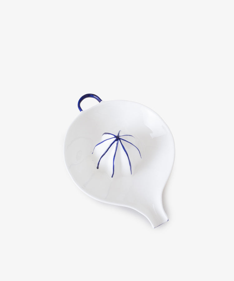 Juicer by Feldspar. White china hand-held citrus squeezer with painted blue accents, overhead view.