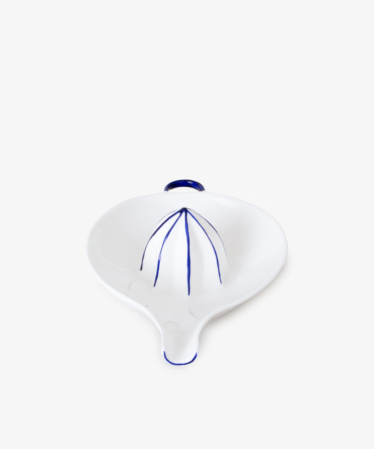 Juicer by Feldspar. White china hand-held citrus squeezer with painted blue accents, front angled view.