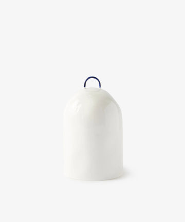 The Salt Pig is a white ceramic seasoning container featuring a blue top handle and minimalist design, perfect for stylishly storing salt.