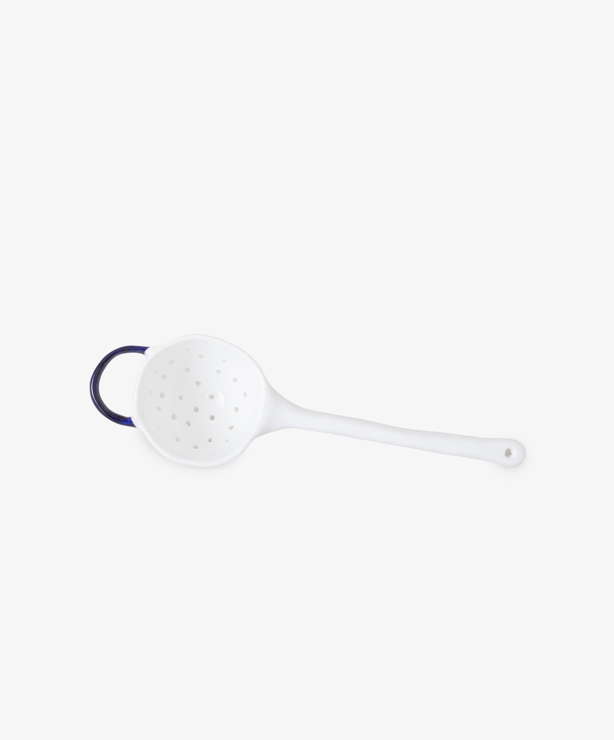 Tea Strainer by Feldspar. White china strainer with cobalt blue painted handle, side view showing strainer holes.