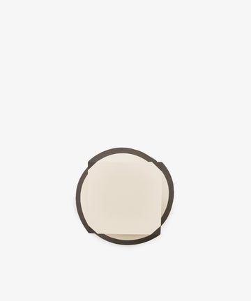 A small, square, cream-colored sheet from the Spiral Notepad sits on top of a larger, round, dark brown coaster against a plain white background.