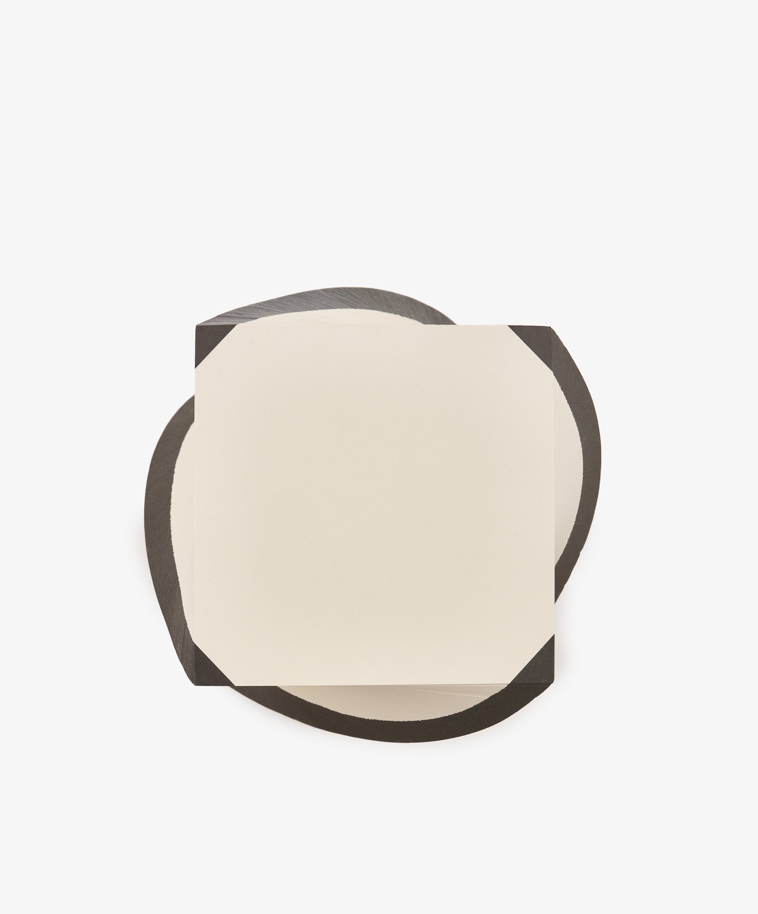 A sheet from the Spiral Notepad, distinguished by its cut corners and square shape, rests on an irregular black surface against a white background.
