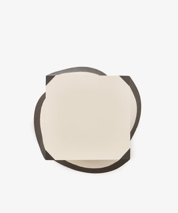A sheet from the Spiral Notepad, distinguished by its cut corners and square shape, rests on an irregular black surface against a white background.