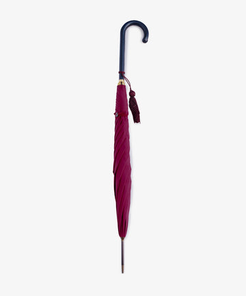 The Victoria Ladies Umbrella, in closed cherry bordeaux, features a curved black leather handle and tassel, standing upright against a plain white background.