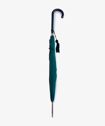 The Victoria Ladies Umbrella is shown closed, featuring a green canopy, a curved dark leather handle with a hanging tassel, and displayed vertically against a plain white background.