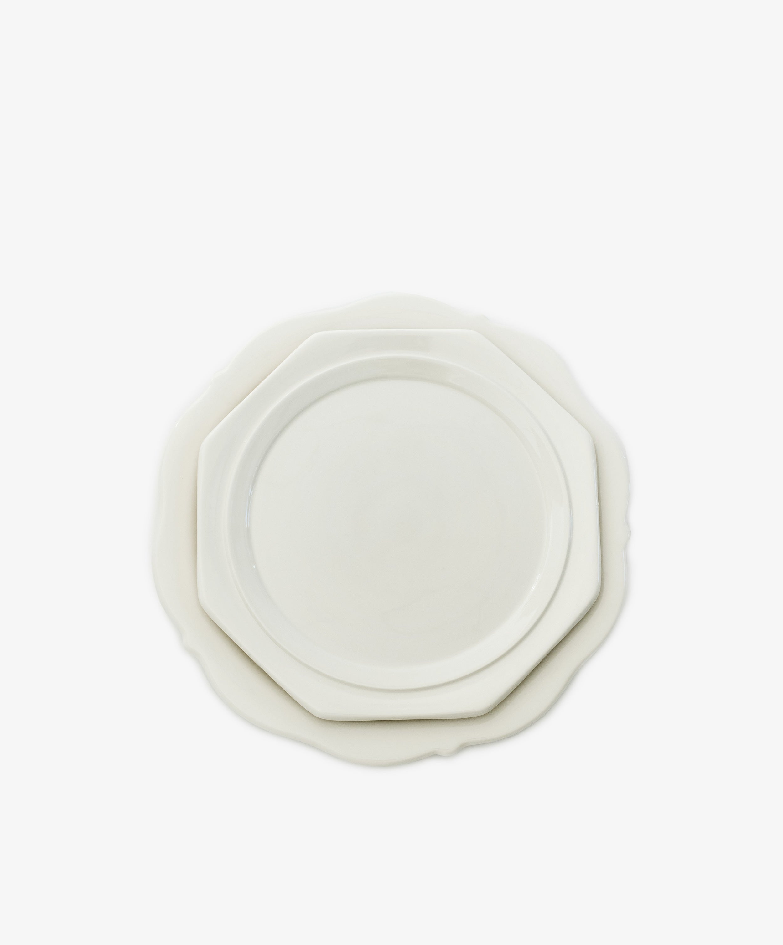 A round white plate and a Cirrus Octagonal Plate in creamware, both reflecting Frances Palmer’s timeless design, are stacked against a plain white background.