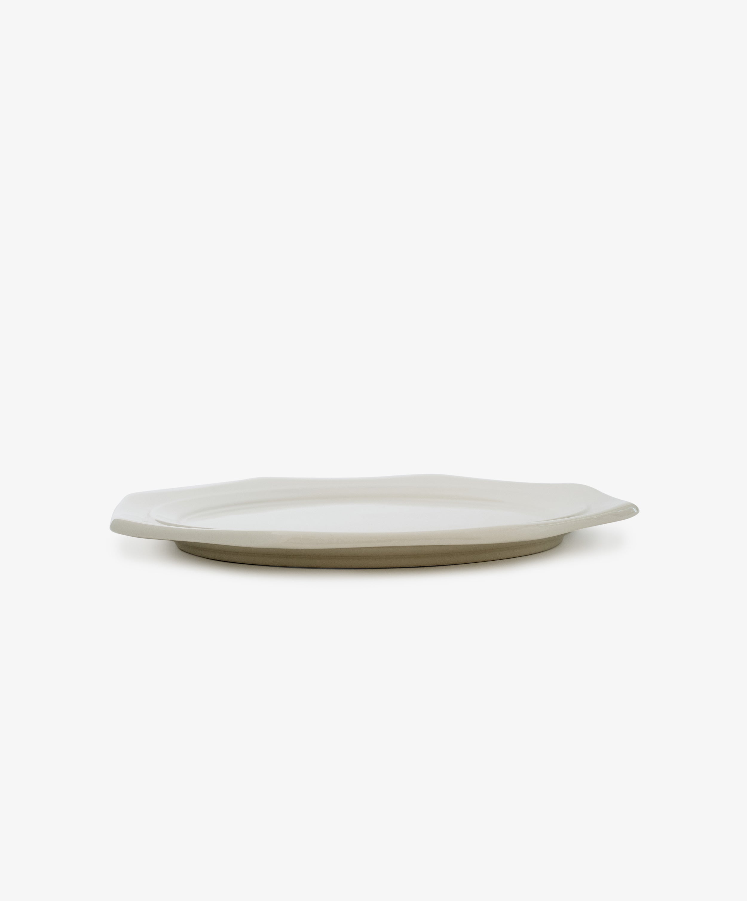 A Cirrus Octagonal Plate is displayed from the side on a white background, its ceramic creamware surface emphasizing simple elegance.