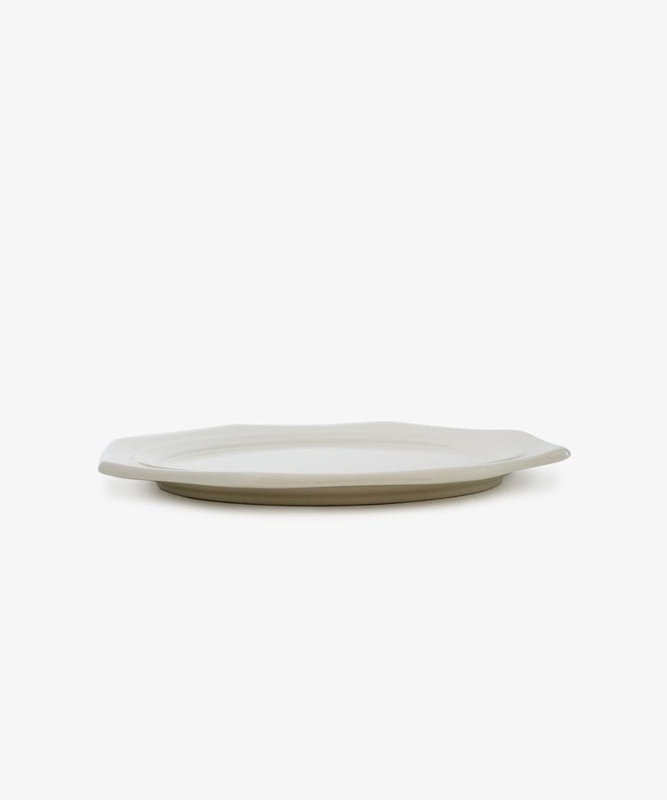 A Cirrus Octagonal Plate is displayed from the side on a white background, its ceramic creamware surface emphasizing simple elegance.