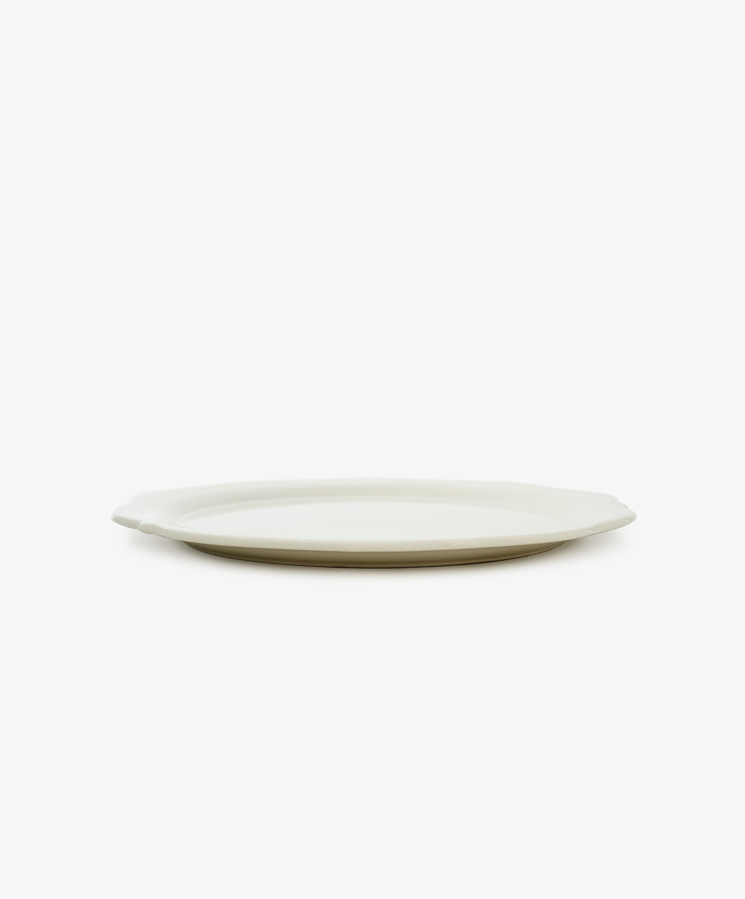 The Cirrus Scalloped Plate, white creamware with a scalloped edge, is shown in side view against a white background.