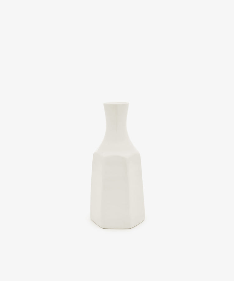 The Cirrus Bud Vase by Frances Palmer is a small, white ceramic piece featuring a geometric design with a narrow neck and hexagonal base, showcased against a plain white background.
