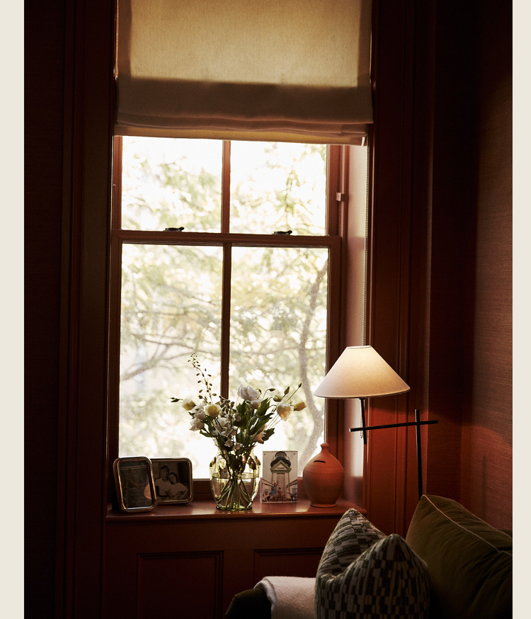 Cozy living room with a window, lamp, and flowers on a windowsill.