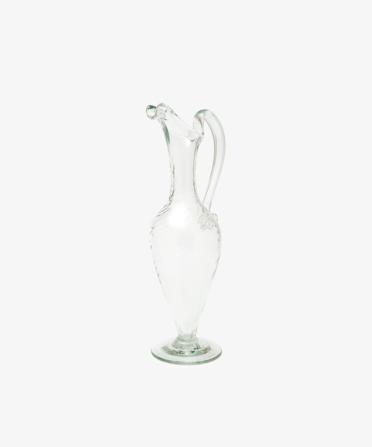 The Alba Vase, a hand-blown glass piece with a narrow neck, curved handle, and decorative spout, stands upright on a plain white background, highlighting its elegant and unique craftsmanship.