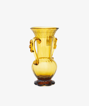 The Camilla Vase is a unique yellow hand-blown glass vase featuring two decorative handles and a flared rim, shown against a plain white background.