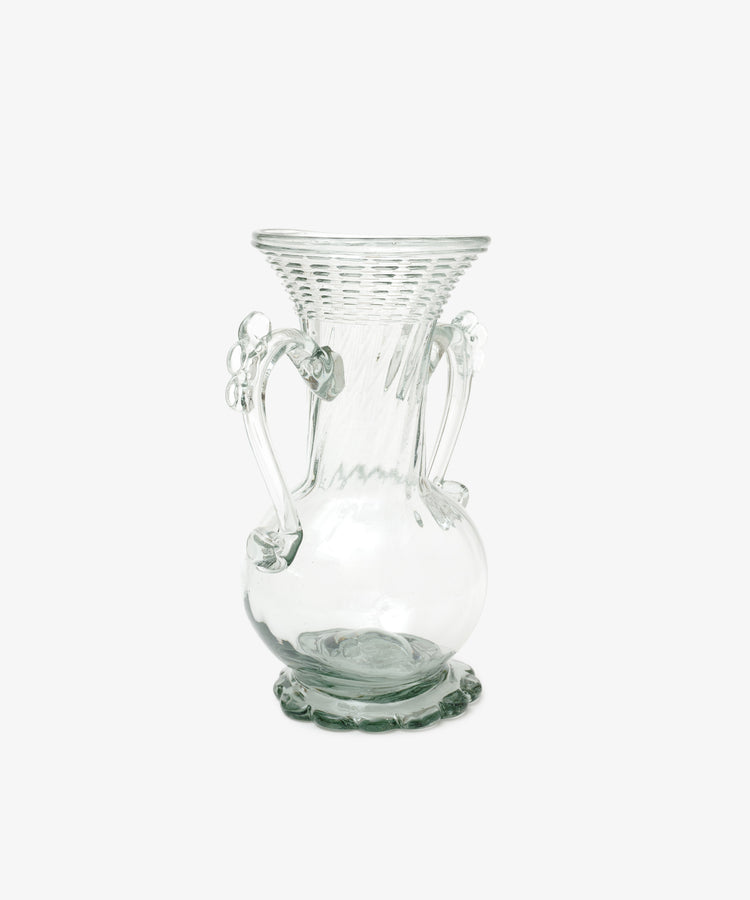 The Camilla Vase is a clear, hand-blown glass vase with a flared textured rim, decorative handles, and a rounded base, highlighting the unique beauty of vases against a plain white background.