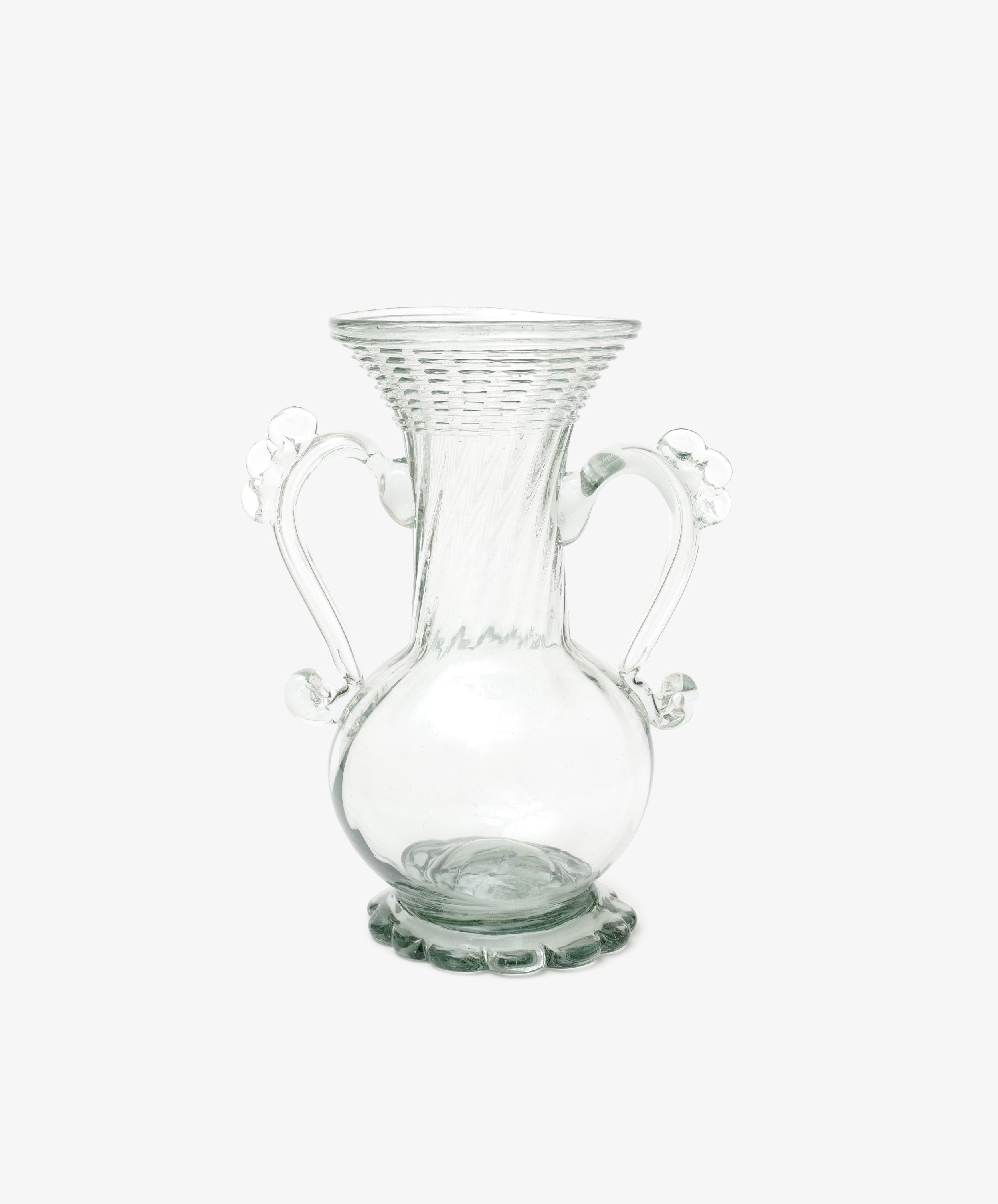 The Camilla Vase is a clear, hand-blown glass piece with a flared rim, two ornate handles, a round base, and decorative detailing—offering a unique artisan touch to your decor.