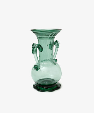 Individually crafted, the Camilla Vase is a green glass piece with two ornate handles and a wide, flared rim, showcasing unique artistry against a plain white background.