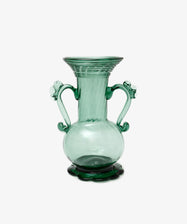 The Camilla Vase is a green hand-blown glass piece with two decorative handles, a wide flared rim, and stands on a scalloped base—individually crafted and set against a white background.