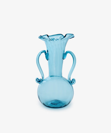 The Camilla Vase is a blue hand-blown glass piece with a round base, two curved handles, and a flared ruffled rim—an eye-catching addition to any collection, shown here against a plain white background.