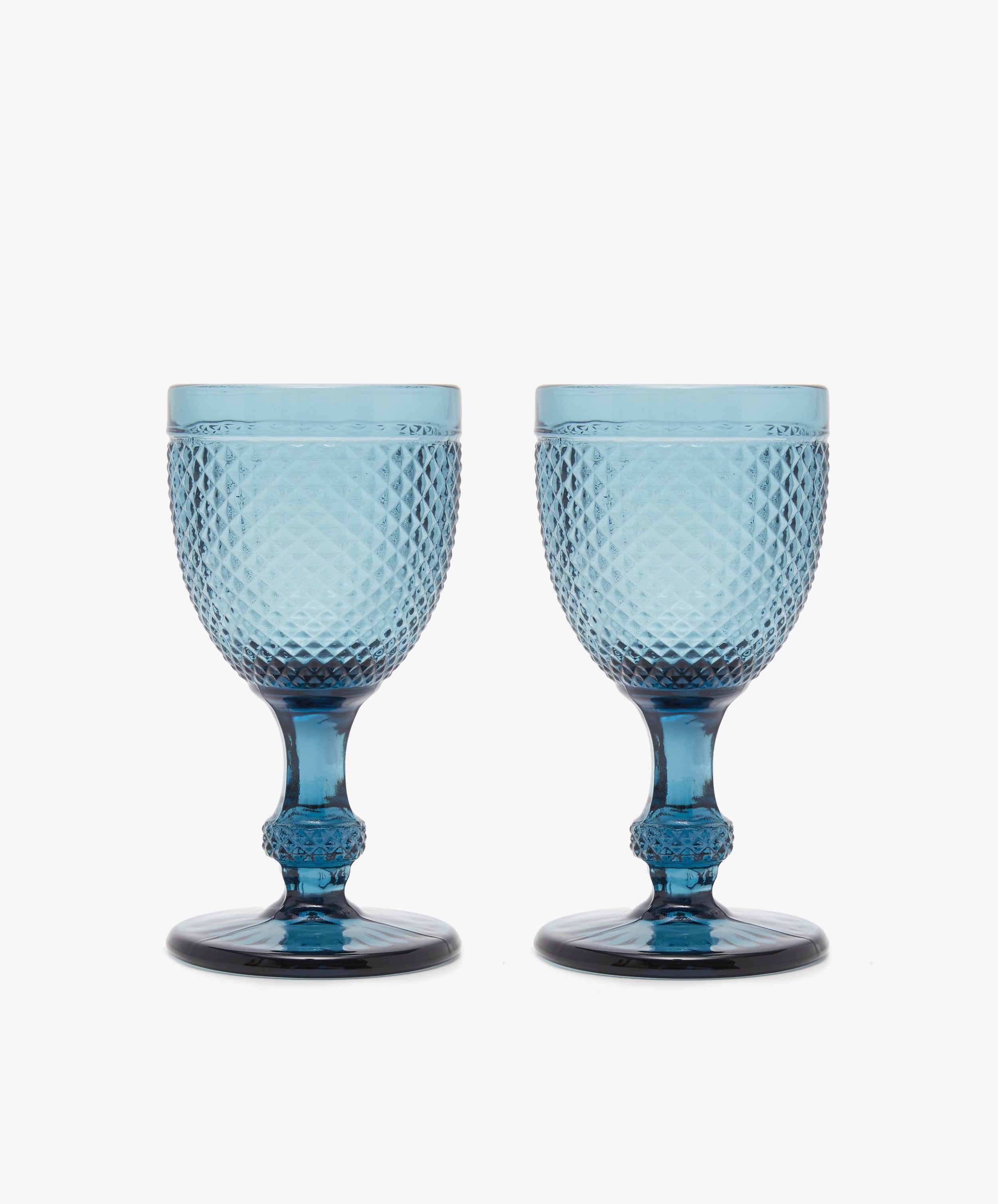 A set of six Celeste Red Wine Glasses, featuring subtle coloring and diamond cut patterns, is arranged side by side on a plain white background.