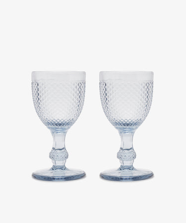 A set of six Celeste Red Wine Glasses with a diamond-cut surface and short stems are arranged side by side on a white background, highlighting their elegant textured design.