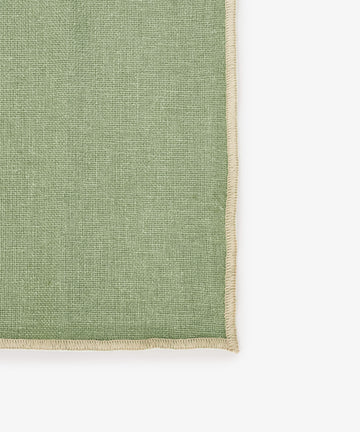 A close-up of the Corte Napkin, Set of 6, in green eco-friendly linen with beige stitched edges, set against a white background—ideal for adding elegance to your table as placemats or napkins.