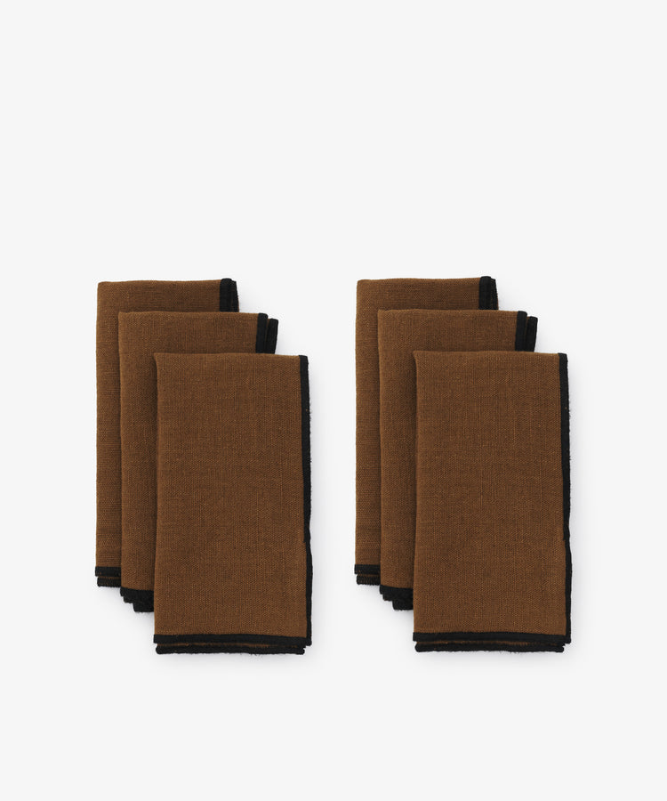 Luri Napkin. Two rows of three napkins in brown linen, with black stitched edges.