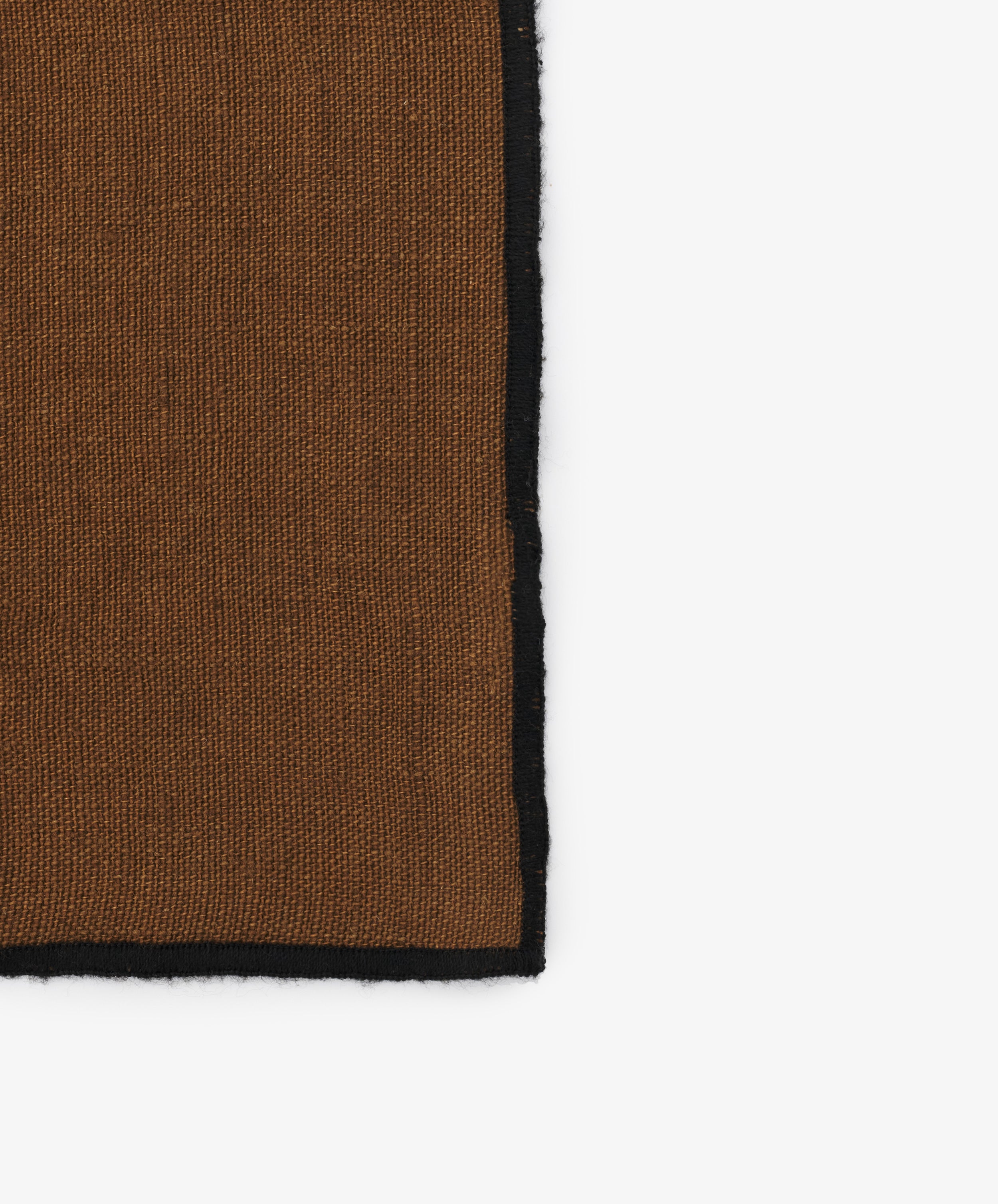 Close-up of black stitched edges on the brown linen Luri Napkin.