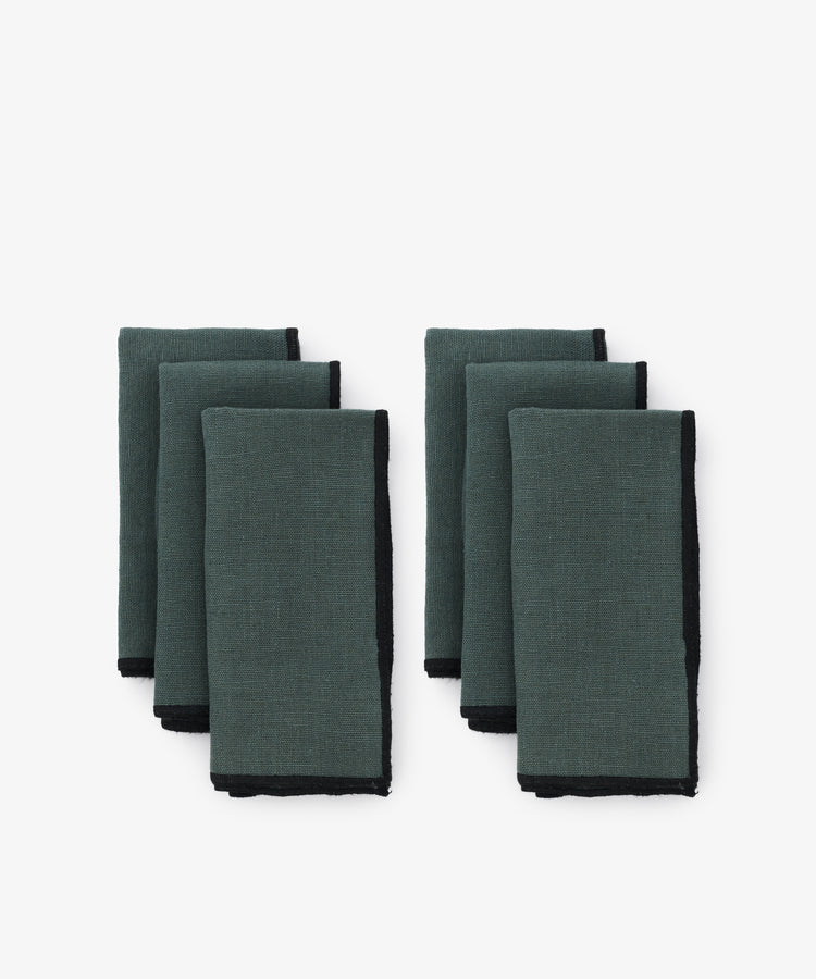 Luri Napkin. Two rows of three napkins in grey-blue linen, with black stitched edges.